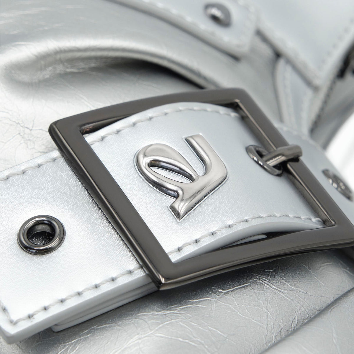 Close-up of a silver buckle on a white leather bag