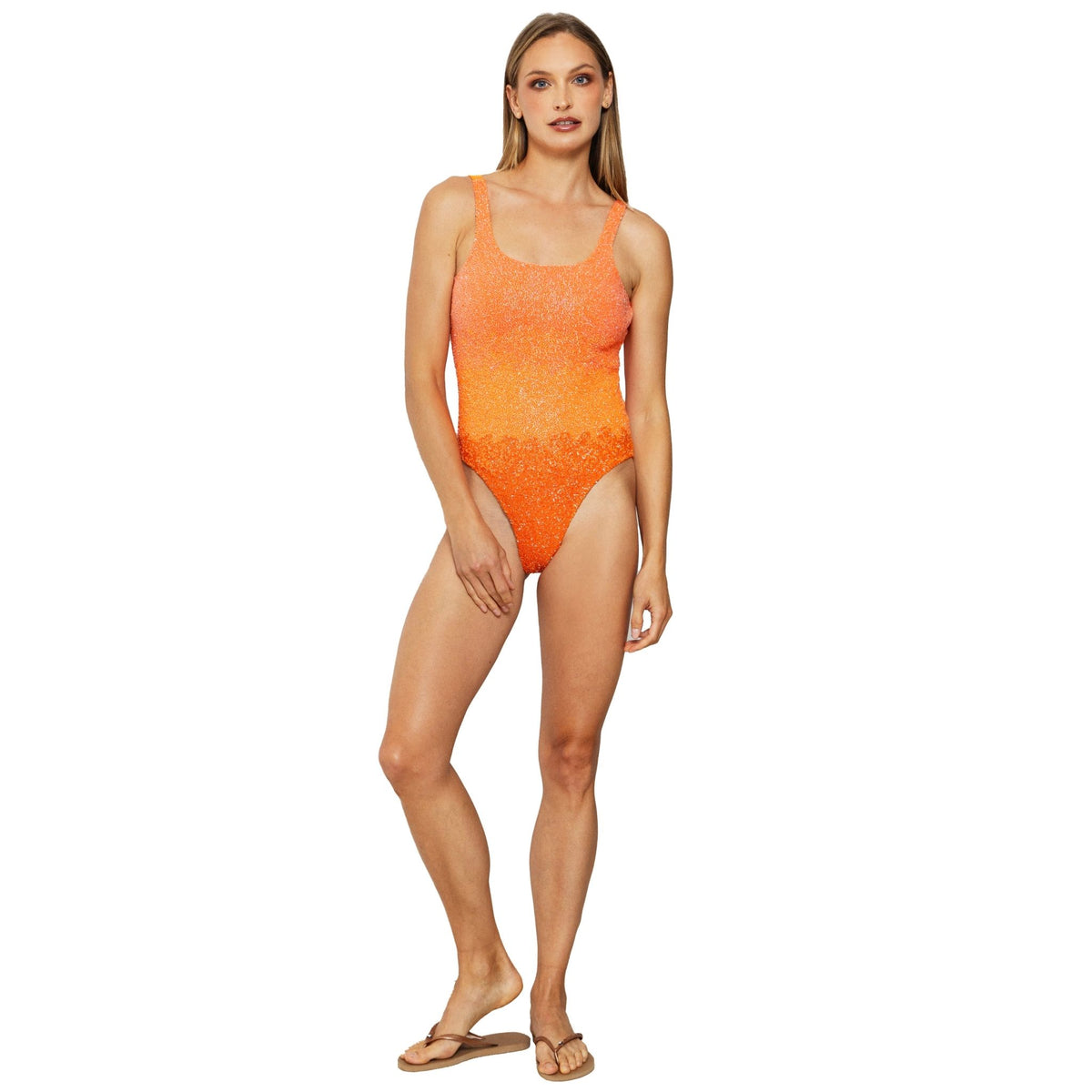 A woman poses in the SELF-ADORE Ombre Hand-Beaded Embellished One-Piece Swimsuit in orange, featuring a scoop neckline and subtle pattern—stylish resortwear ideal for sunny getaways.