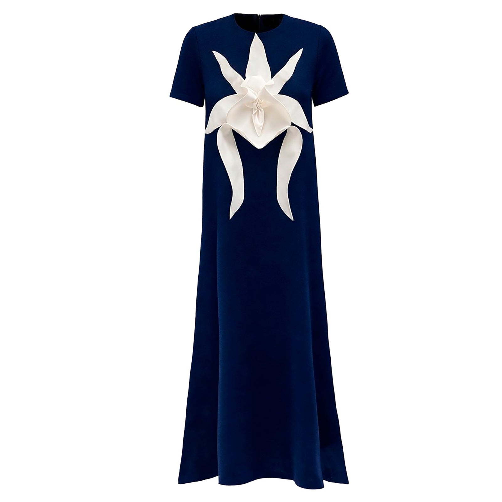 The JULIA ALLERT Ankle-Length Knit Dress With Flower Detail in dark blue features short sleeves and a striking white sculptural floral appliqué on the chest.