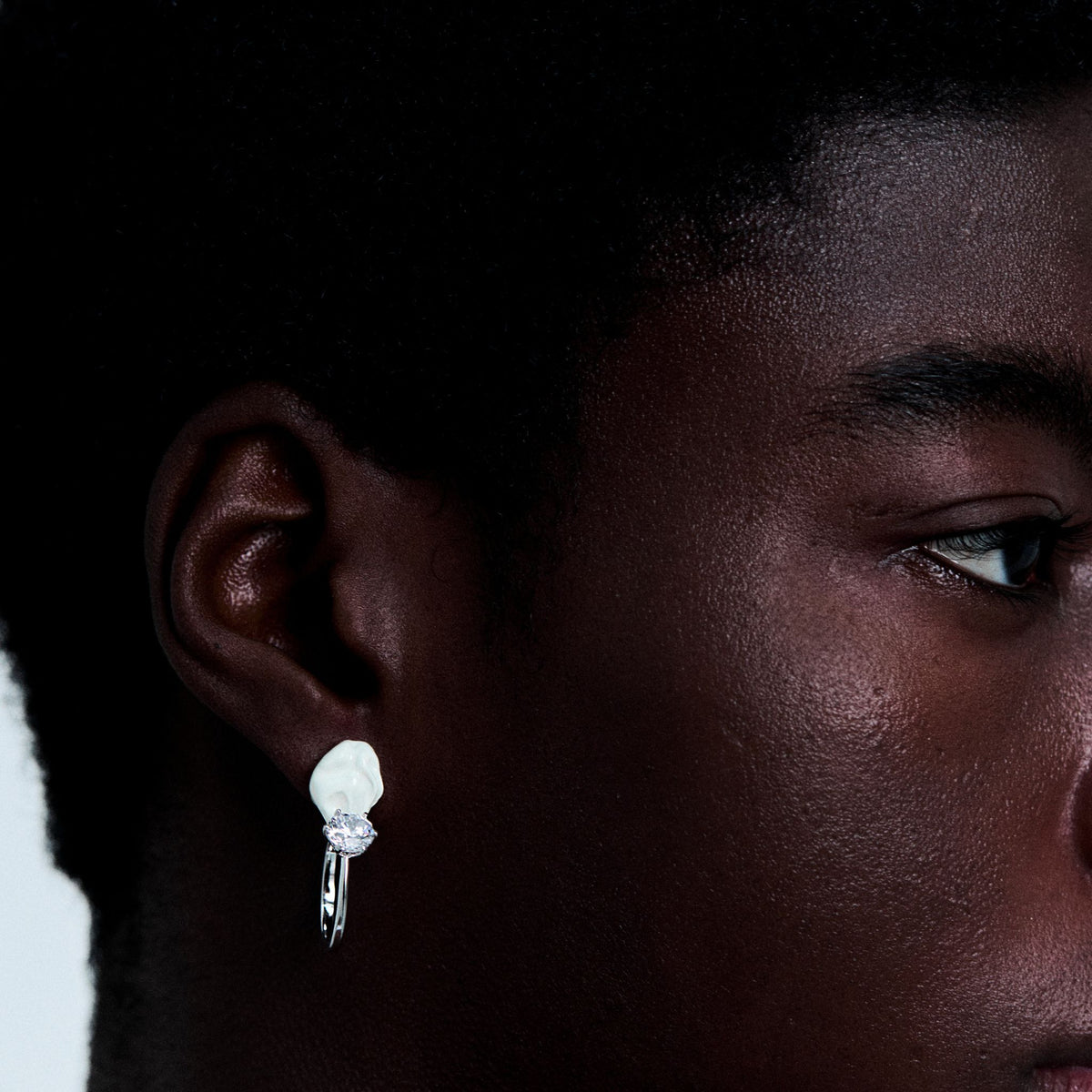 Close-up of a person wearing a diamond earring with a dark background