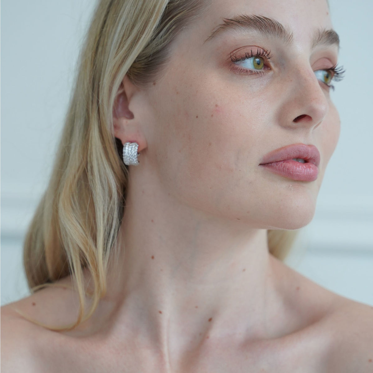 Close-up of a woman wearing diamond hoop earrings with a blurred background