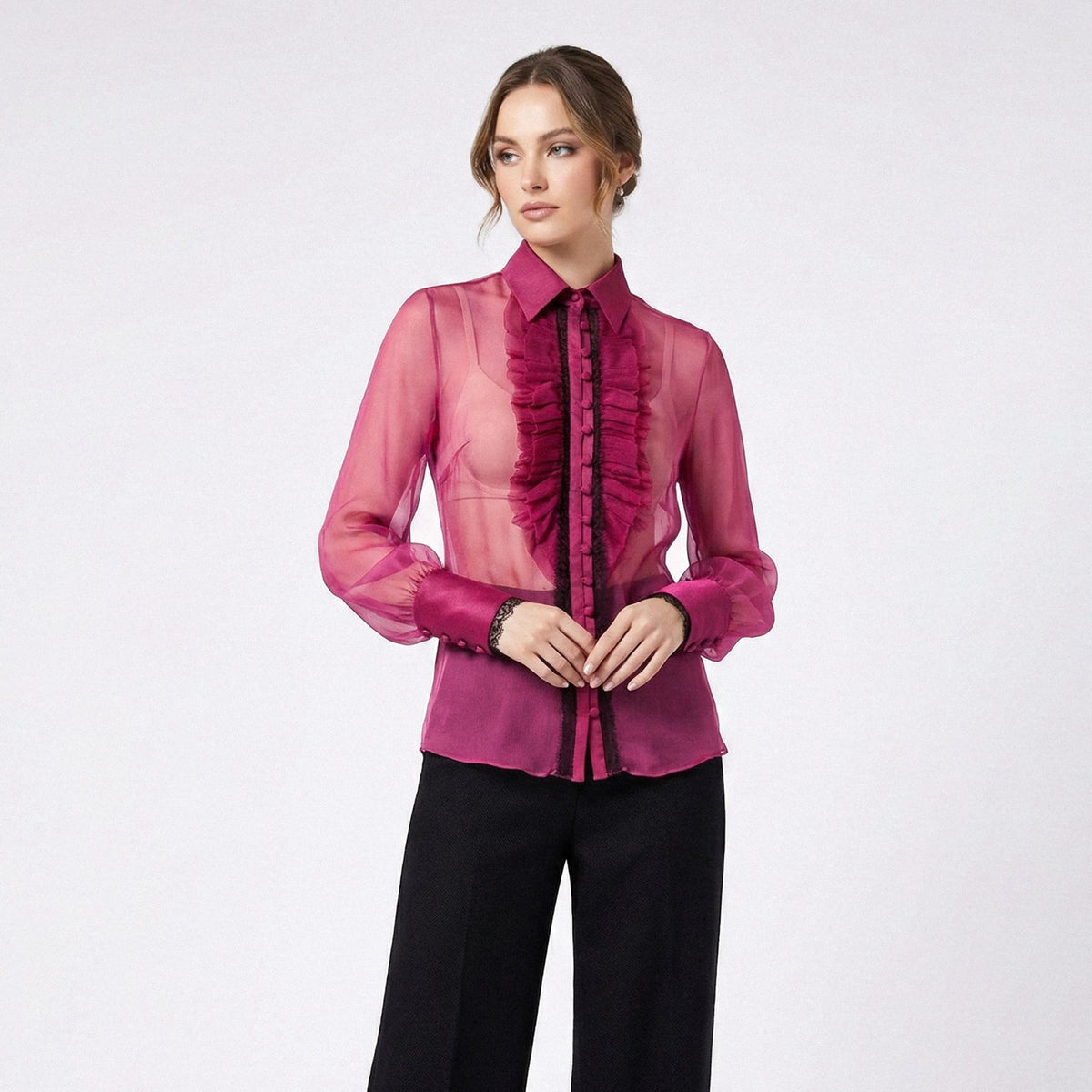 Woman wearing a pink sheer blouse with ruffles on a white background