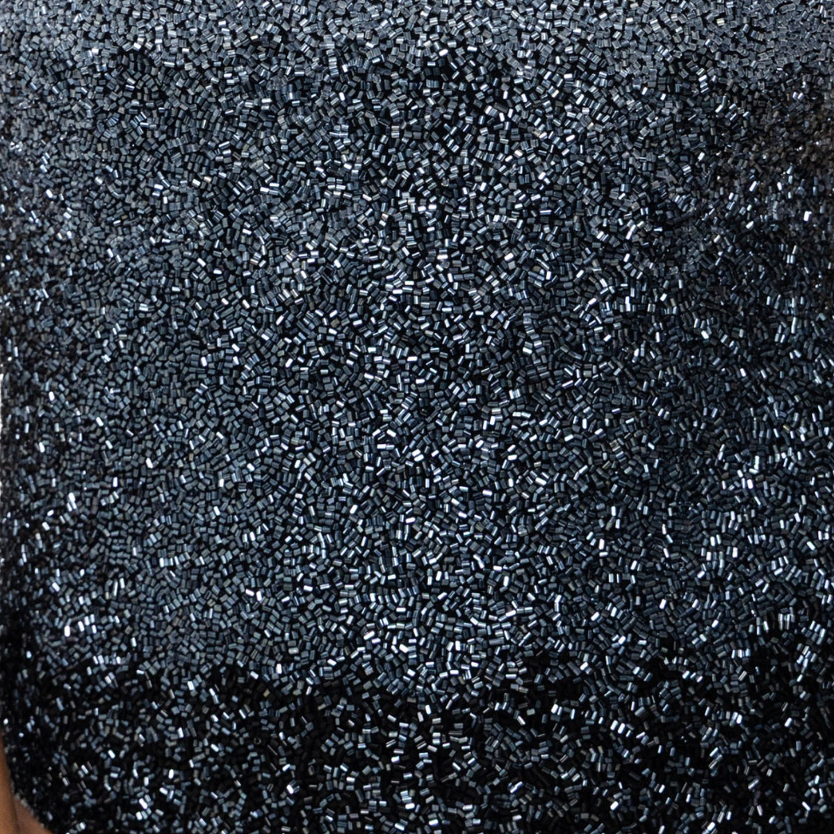 Close-up of SELF-ADORE’s Ombre Hand-Beaded Embellished One-Piece Swimsuit in Black, featuring a dense, textured pattern of tiny shiny black and silver beads, adding a sparkling luxury resortwear touch.