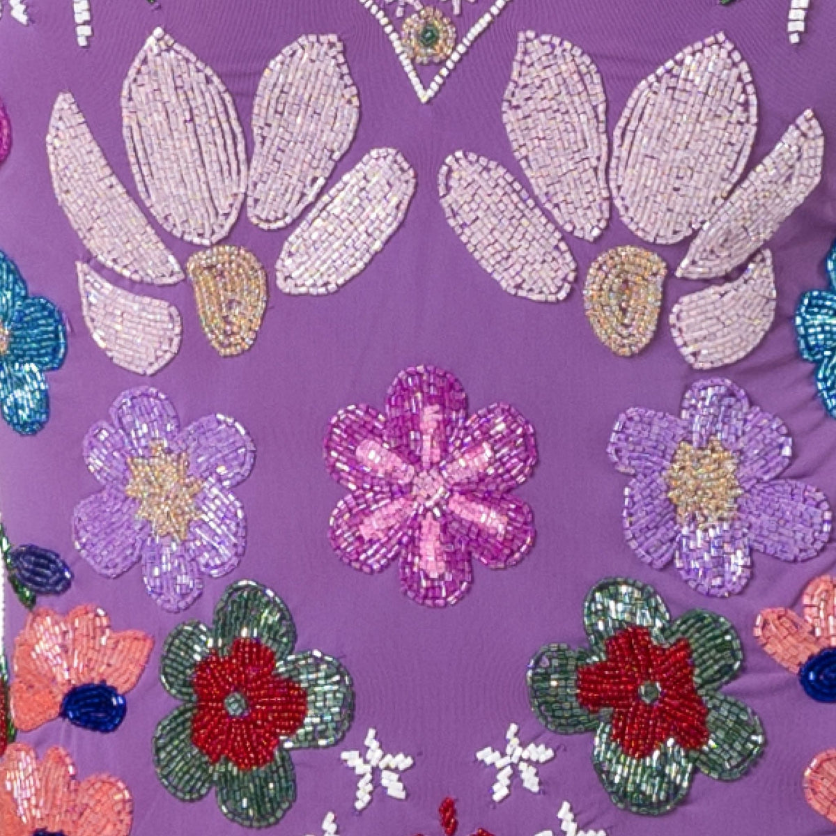 A close-up of the SELF-ADORE Flower Hand-Beaded Embellished One-Piece Swimsuit in purple, showcasing intricate beadwork with colorful floral patterns in pink, purple, green, and red.