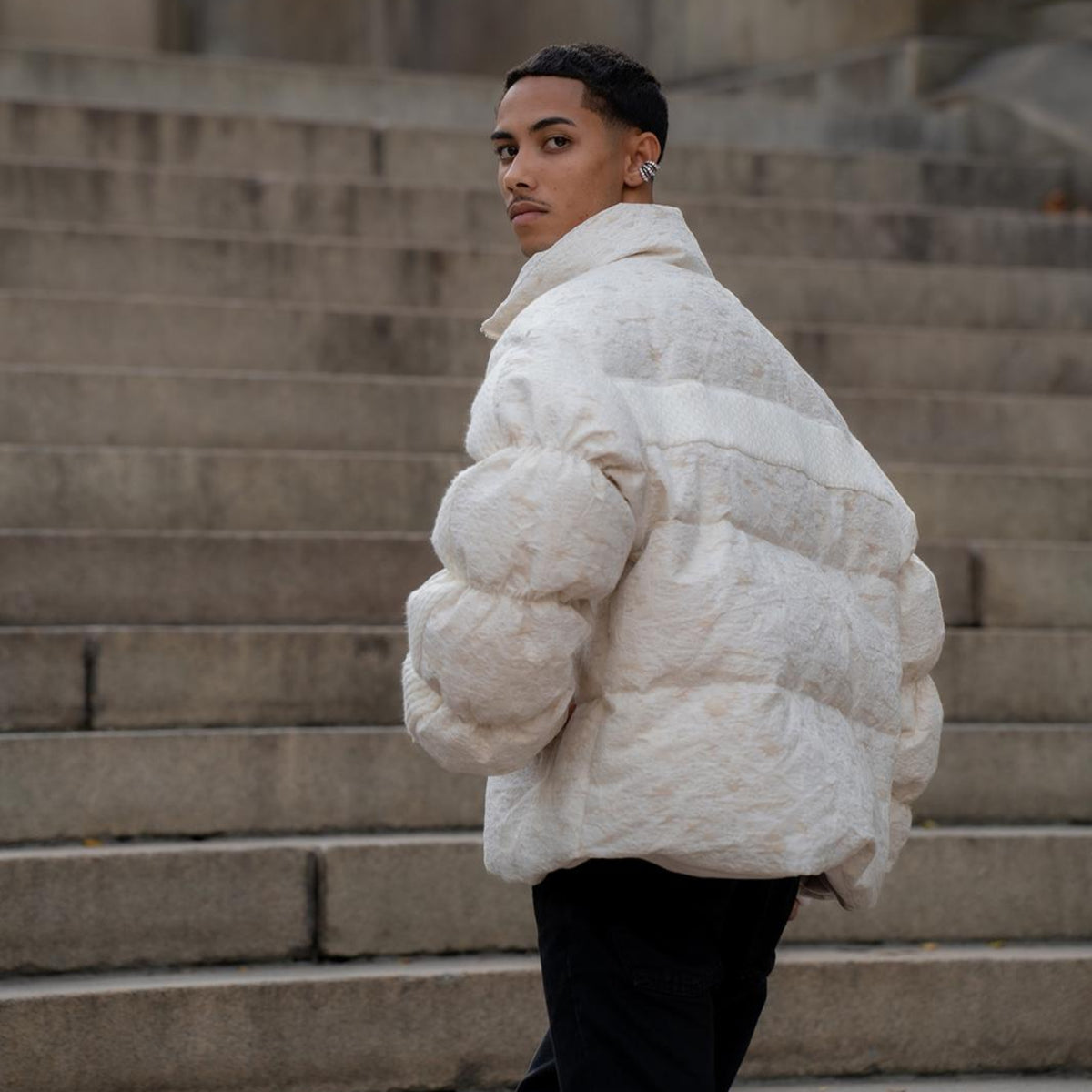 Person wearing a white puffer jacket standing on stone steps.