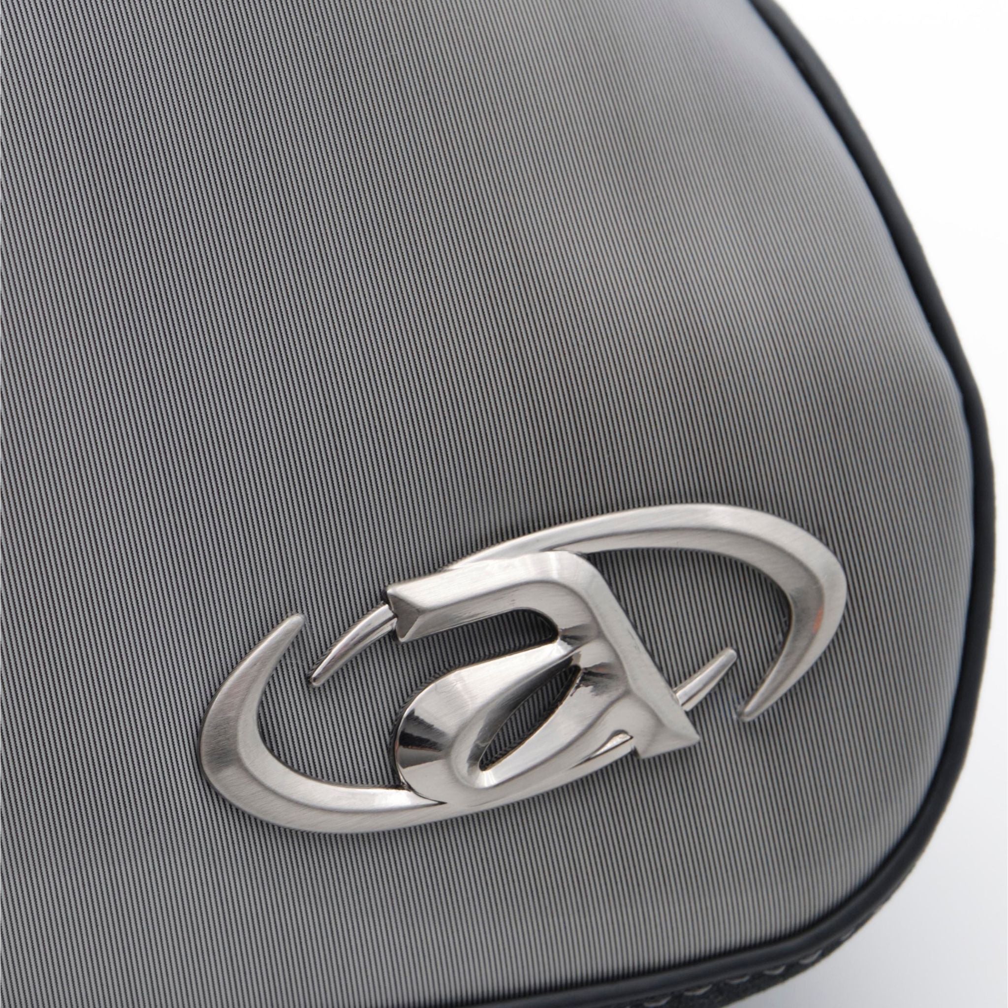 Close-up of Ada crossbody bag with signature metal logo and top zip closure