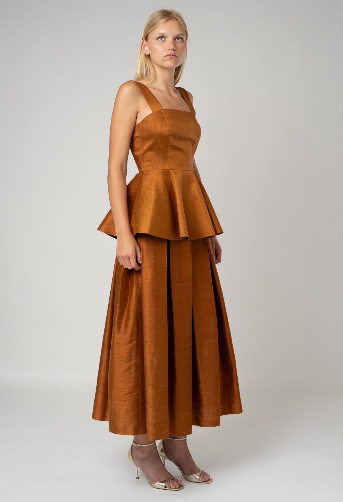 Woman wearing a brown dress with a peplum top on a white background