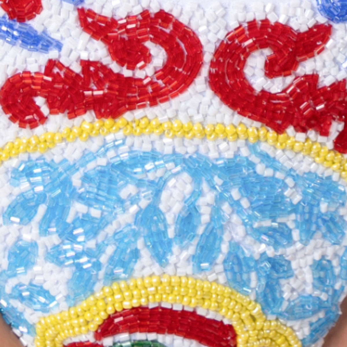 Close-up of intricate beadwork on the SELF-ADORE Limoncello Hand-Beaded Embellished Bikini Bottom in white, featuring ornate red, blue, yellow, green, and white bead patterns.