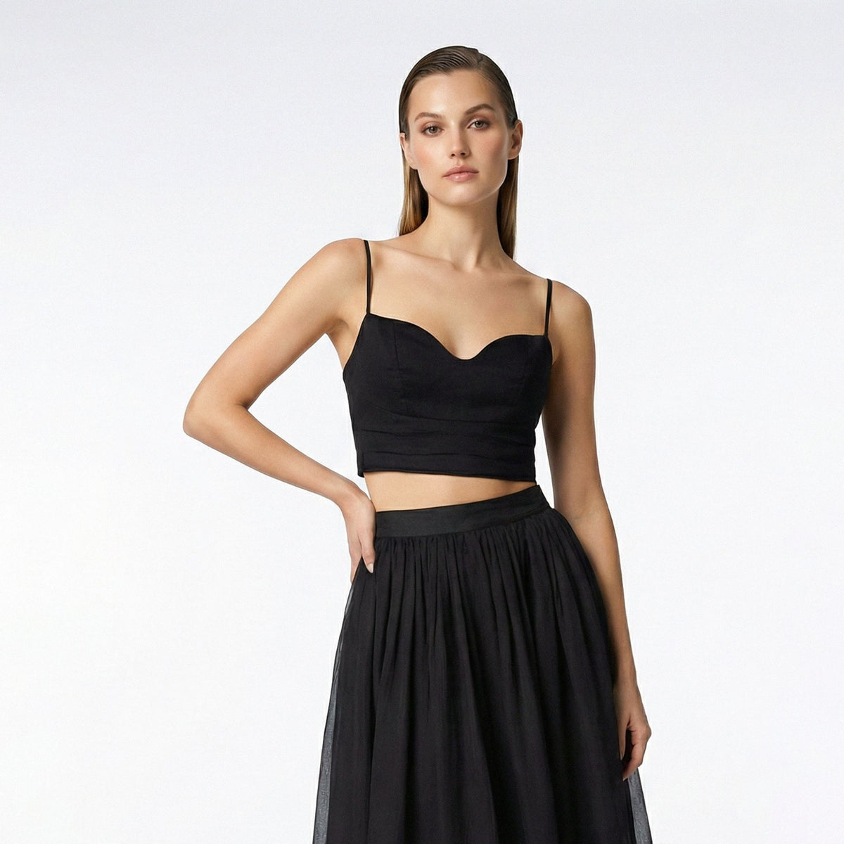 Woman wearing a black top and black skirt on a white background