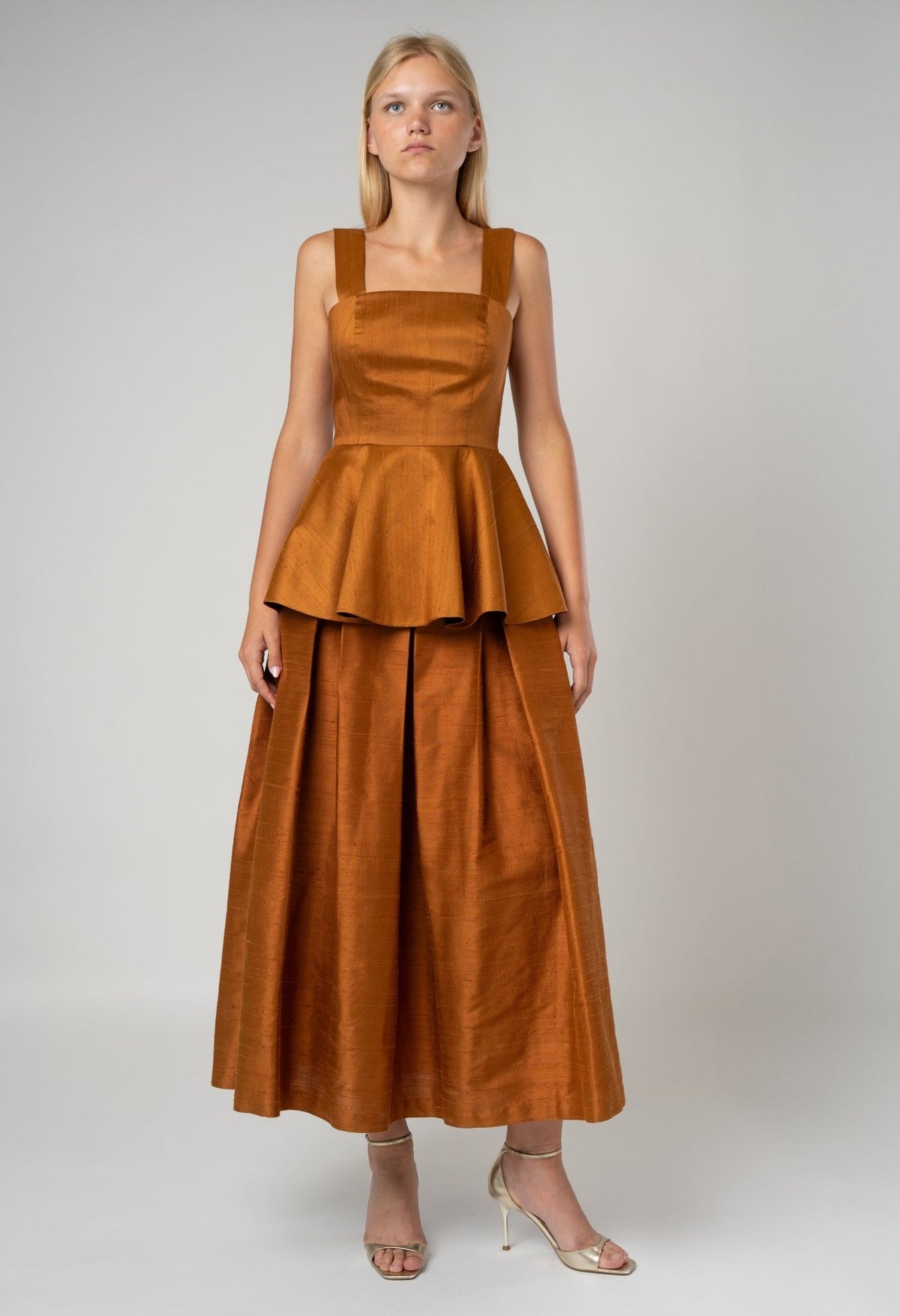 Woman wearing a brown dress with a peplum top on a white background