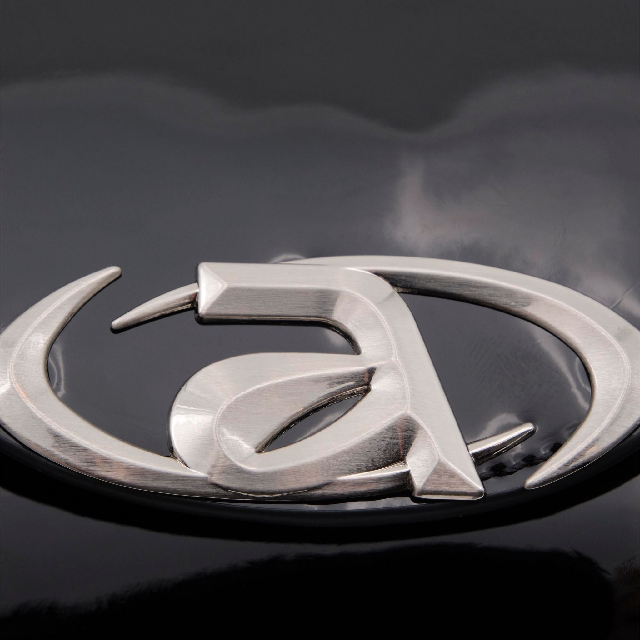 Close-up of a silver car emblem on a dark background