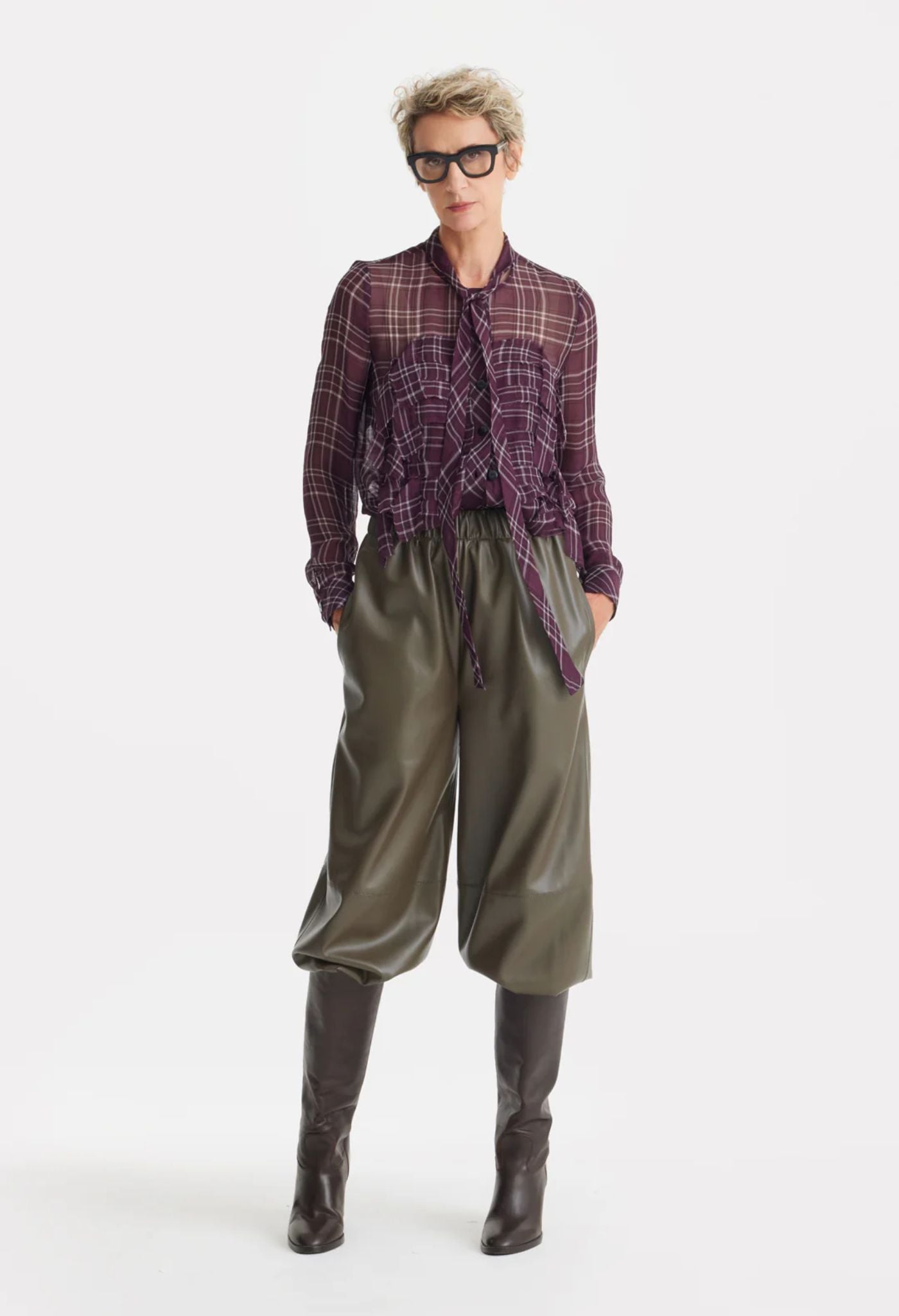 Person wearing a plaid shirt, green pants, and brown boots on a white background