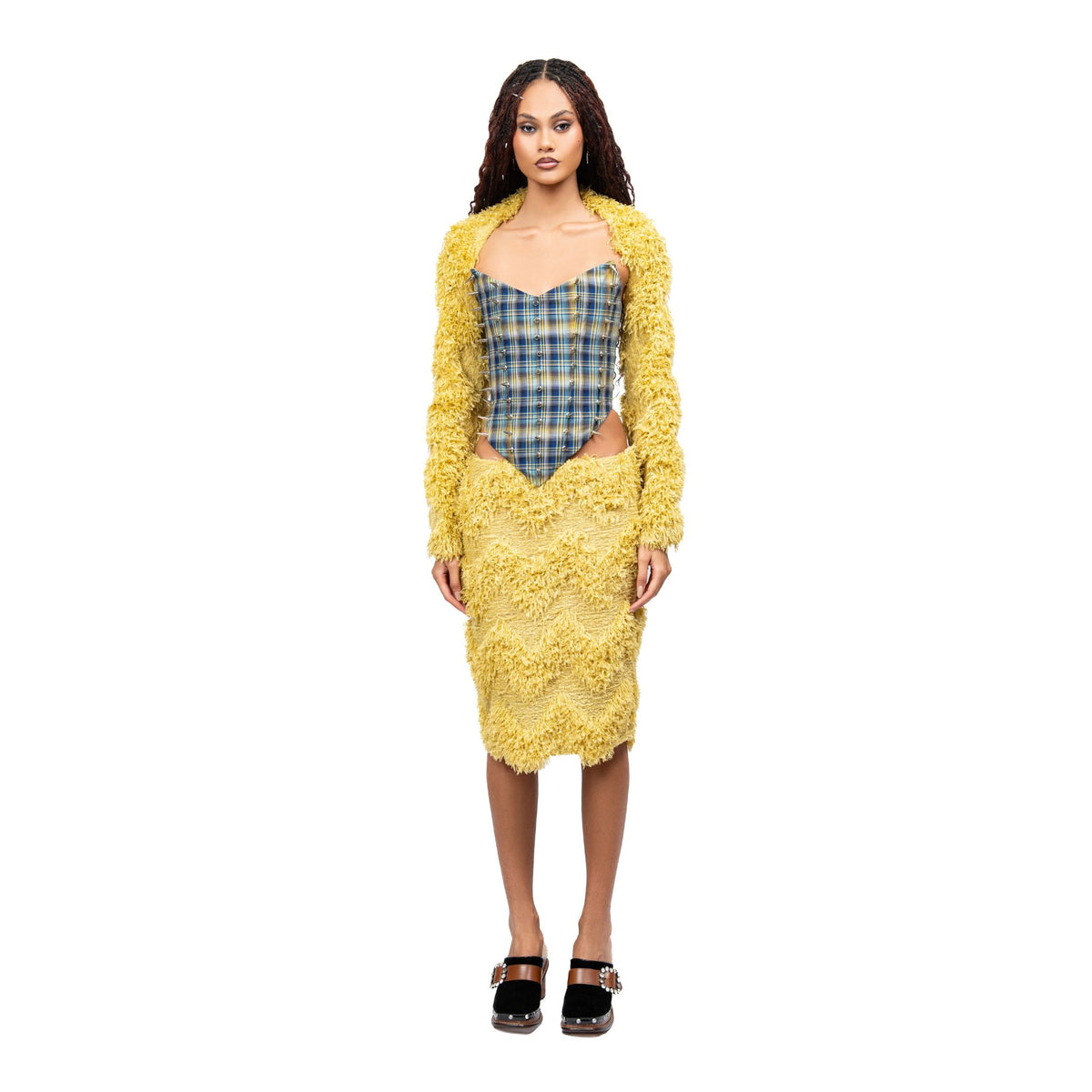 Woman wearing a yellow floral dress over a plaid top on a white background