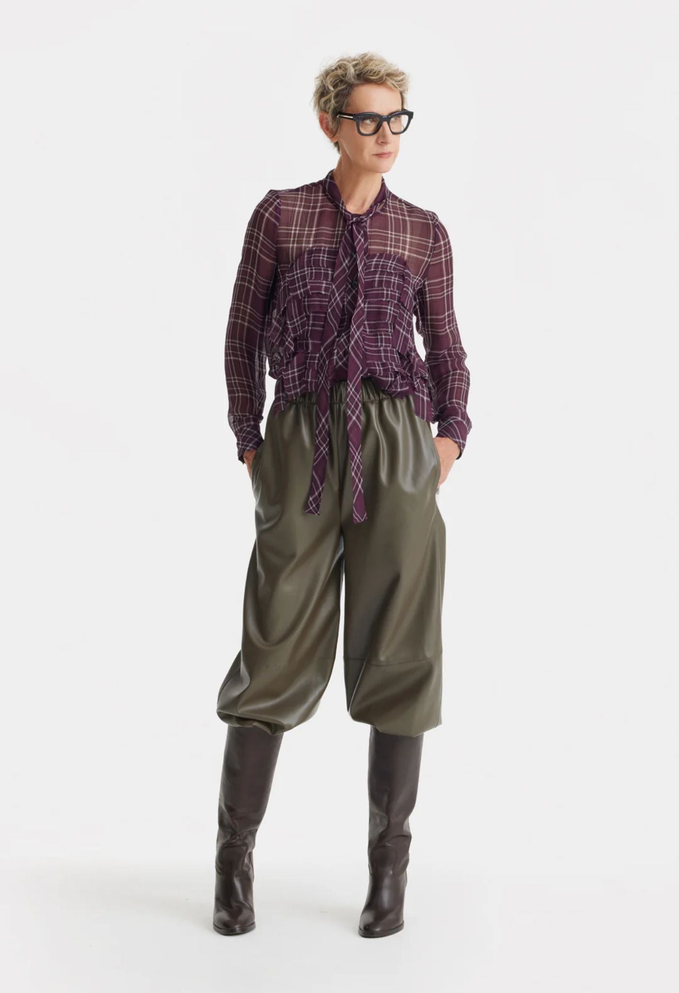 Person wearing a plaid shirt, green pants, and black boots on a white background