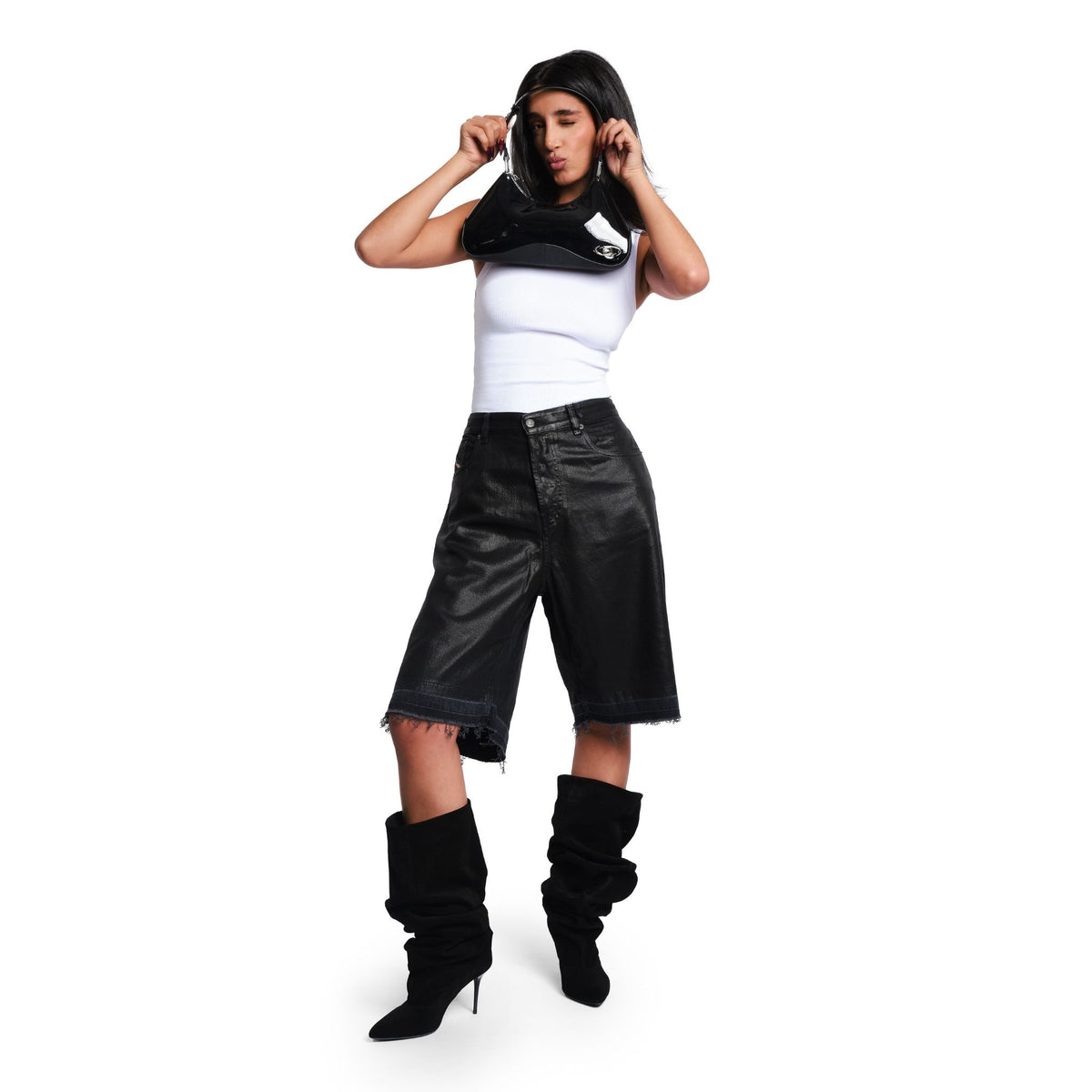 Person wearing a white crop top, black leather shorts, and black knee-high boots on a white background