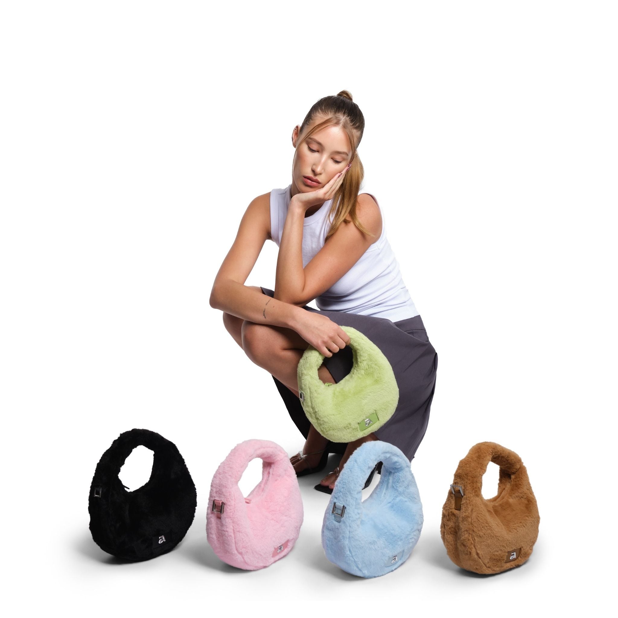 Woman sitting with a green pillow, surrounded by five colorful pillows on a white background