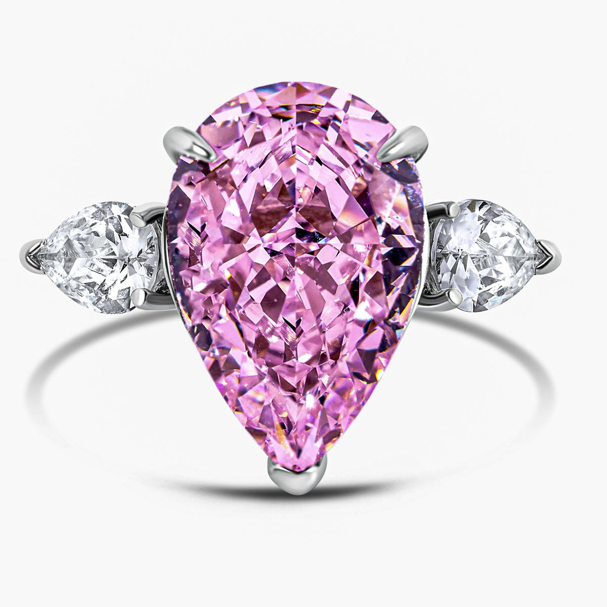 Ring with a pink pear-shaped diamond and two smaller diamonds on a white background