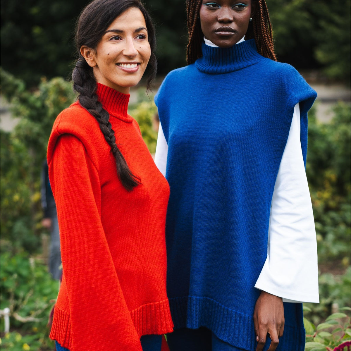 Two women wearing colorful sweaters standing outdoors with a blurred background