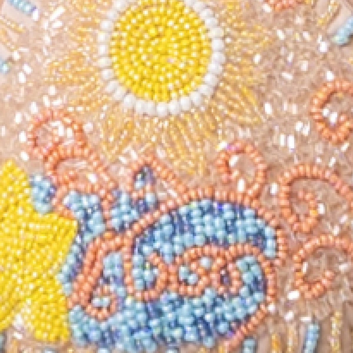 Close-up of colorful beadwork on the SELF-ADORE High Tide Hand-Beaded Embellished Bikini Top in Sand, featuring a yellow sun, star, and swirling blue, pink, and peach patterns for a vibrant look.