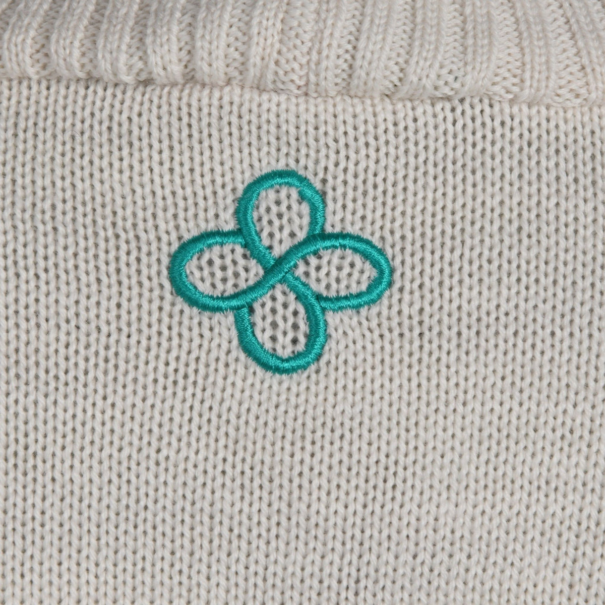 Close-up of a textured fabric surface with a teal embroidered flower design.
