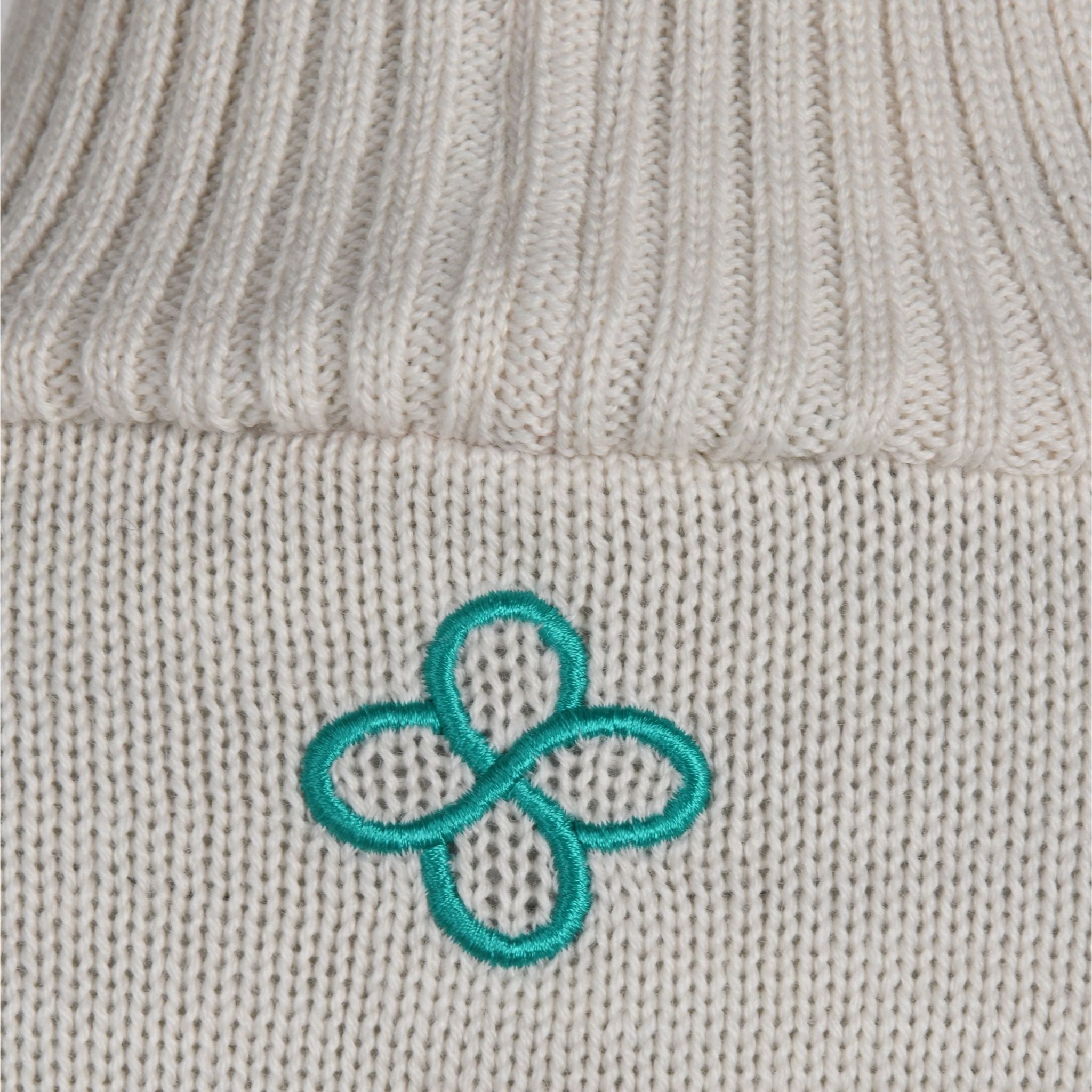 Close-up of a gray knit fabric with a teal embroidered flower design.
