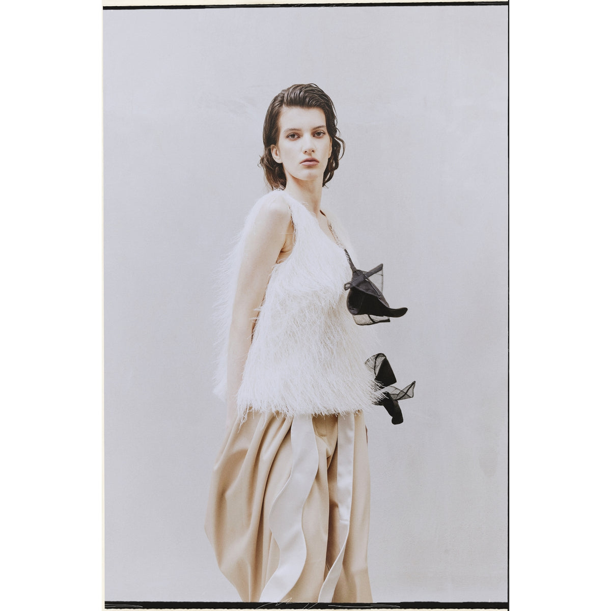 A person with short, dark hair wears the JULIA ALLERT Fringe Sleeveless Top in ivory and a long beige skirt with flowing panels, standing against a plain light background.