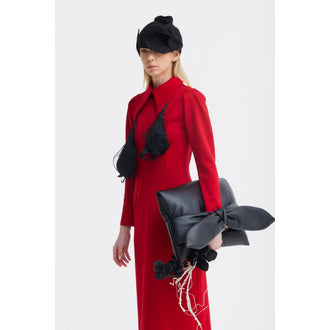 A woman with straight blonde hair wears a red JULIA ALLERT Solid Formal Midi Dress and a black hat, holding an oversized black clutch adorned with a large bow, black flowers, and white twigs against a plain white background.