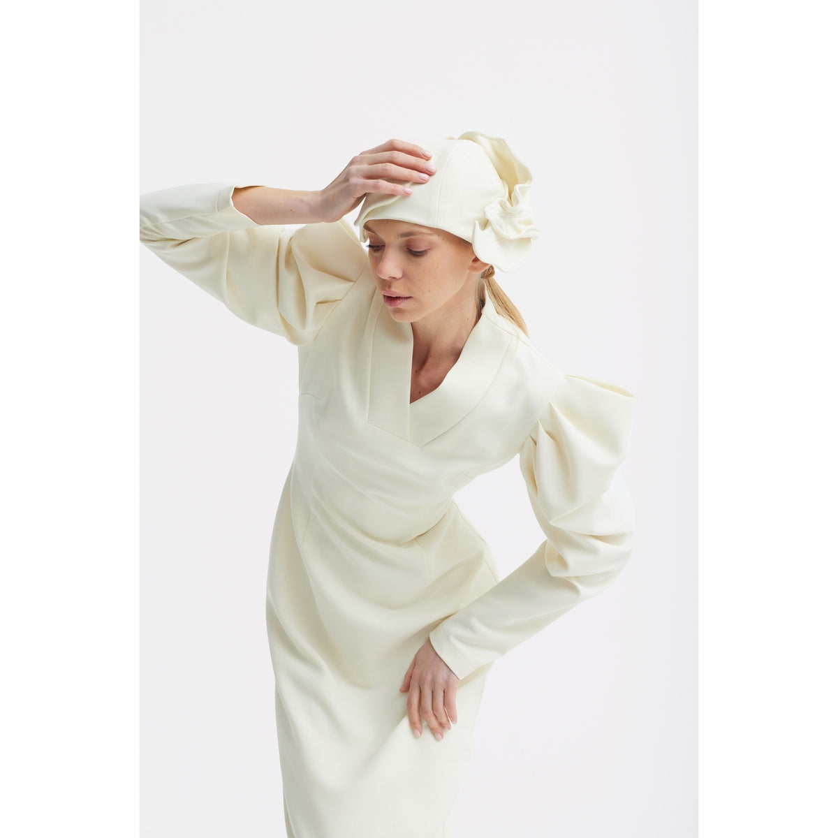 A woman models the JULIA ALLERT Crepe Midi Dress With Statement Sleeves in ivory, paired with a matching headscarf featuring a soft fabric flower, against a plain white background.