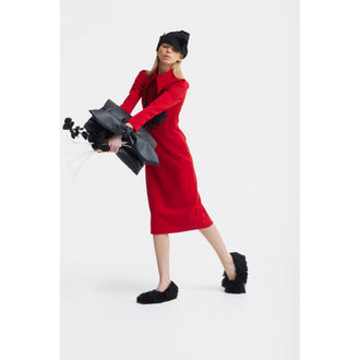 A woman in a JULIA ALLERT Solid Formal Midi Dress - Red and black fuzzy slippers poses on one leg, holding a bouquet wrapped in black paper. She wears a black hat over her eyes, standing against a plain white background.