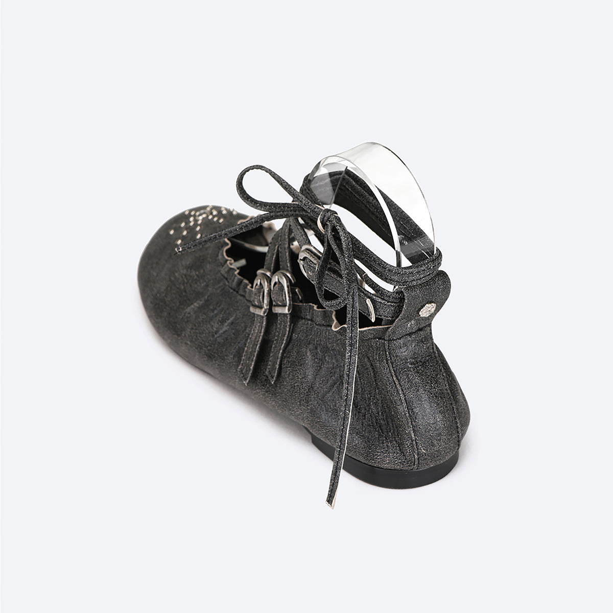 A single black distressed THEN Lace-Up Ballerina Flat for children, handcrafted in Korea, with decorative cutouts, two buckled straps, and wraparound bow laces, is displayed on a light background.