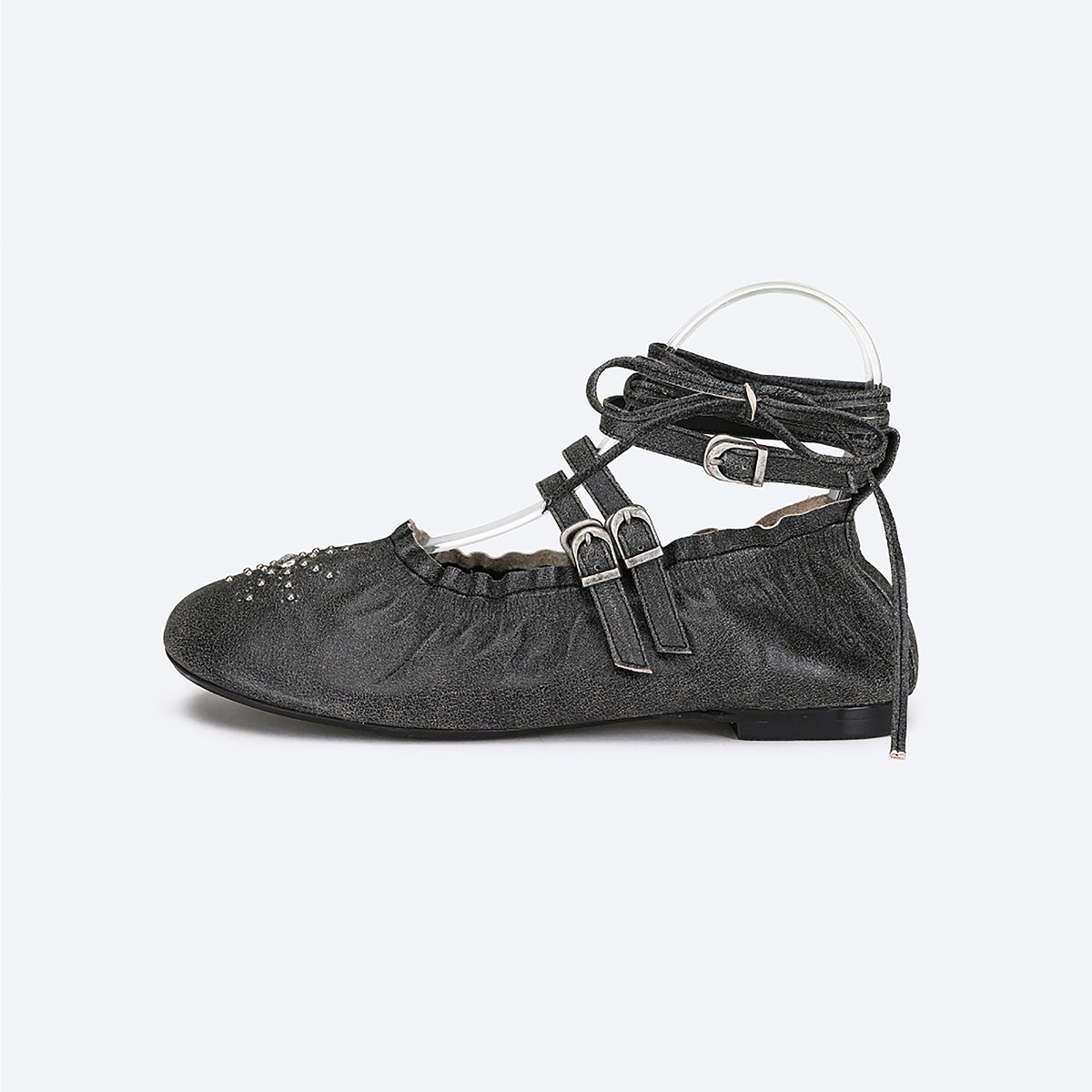 The THEN Black Distressed Lace-Up Ballerina Flats, handcrafted in Korea, feature two side buckles, wraparound laces, decorative stitching, and toe embellishments—all displayed in a sleek side profile on a plain background.