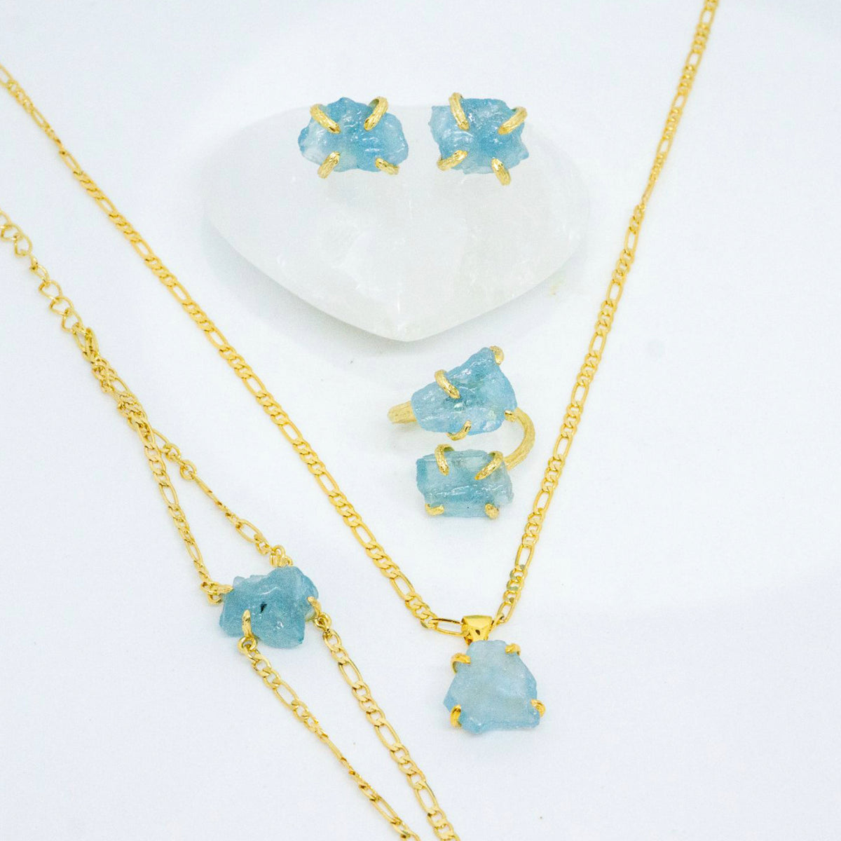 Jewelry set with gold necklaces and earrings featuring blue gemstones on a white background
