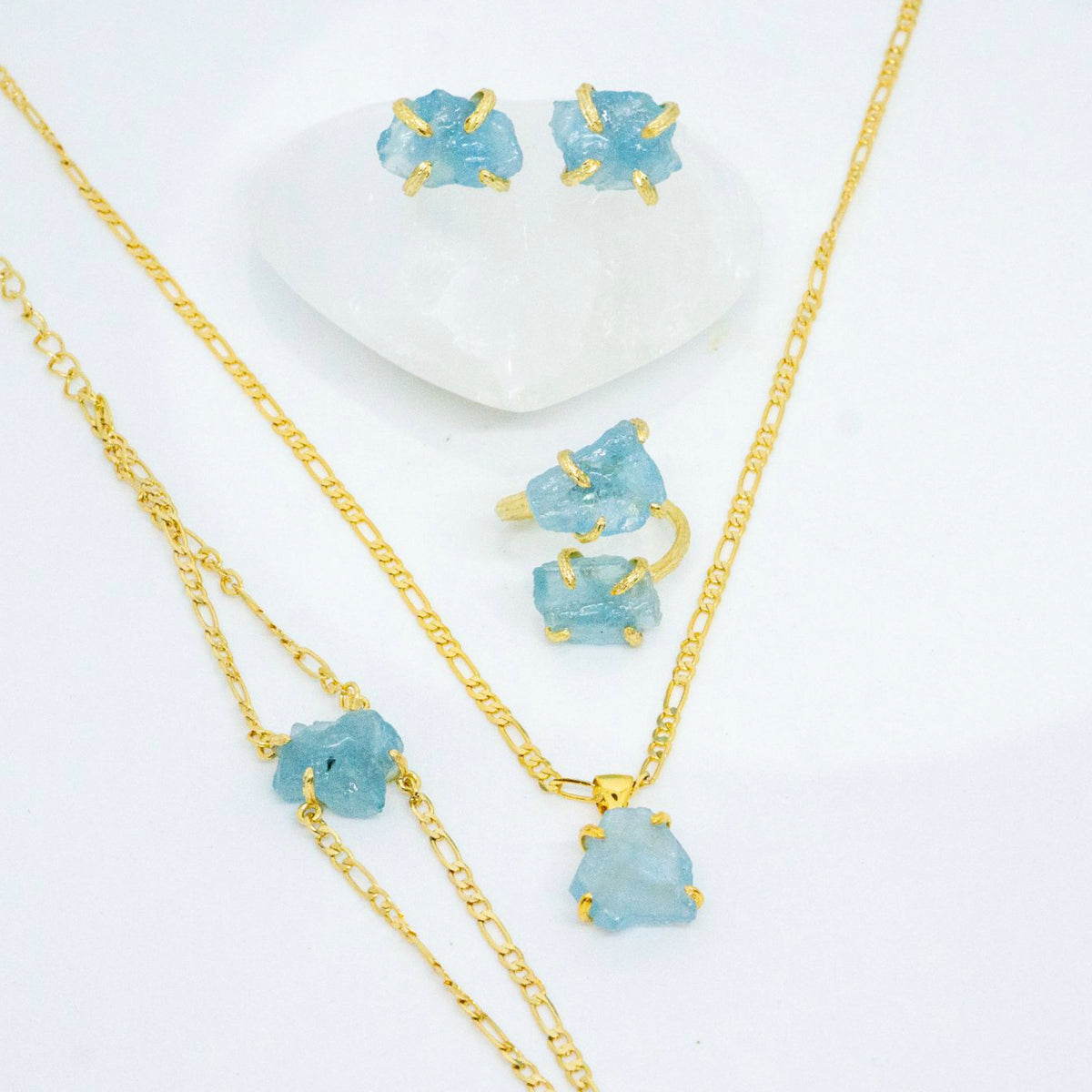 Gold necklace and earrings with blue gemstones on a white background