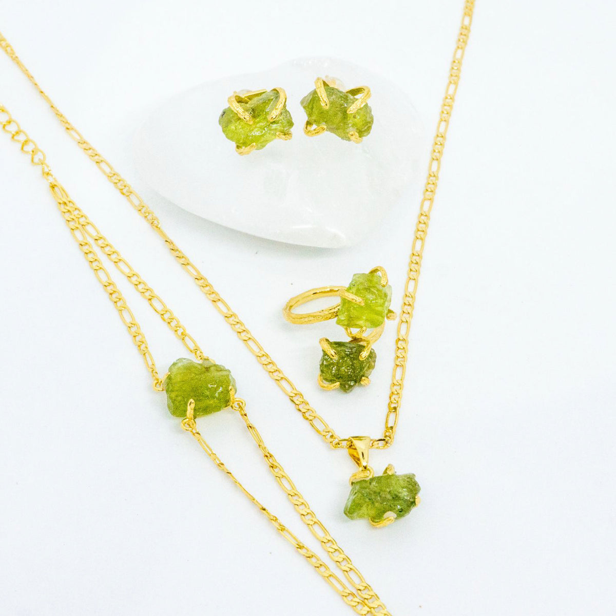 Gold jewelry set with green gemstones on a white background