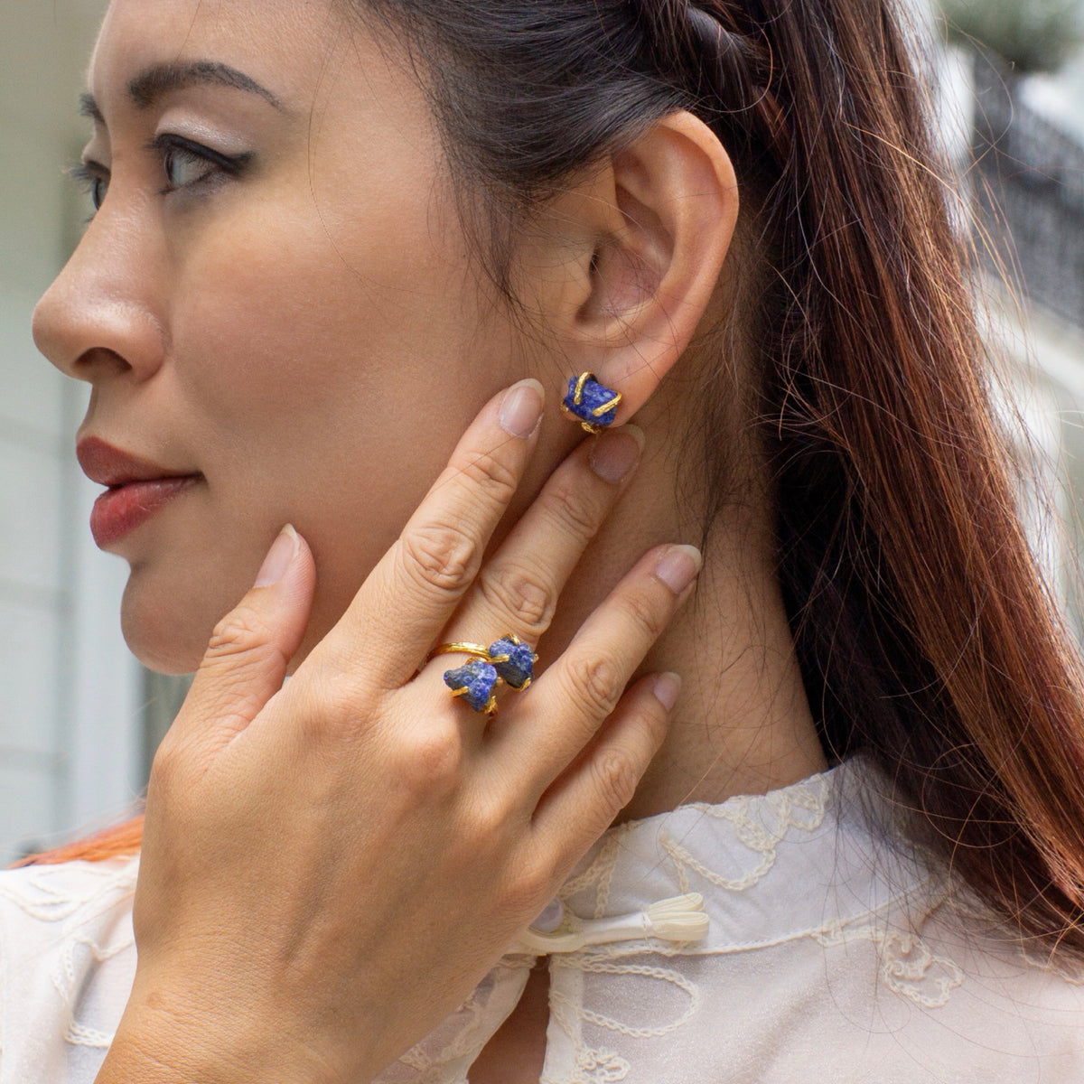 Woman wearing a blue earring and ring, with a blurred background