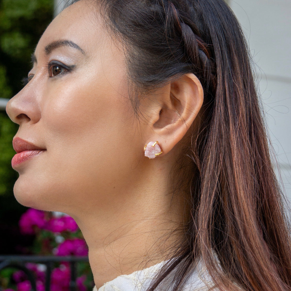 Close-up of a woman wearing pink floral earrings with a blurred background
