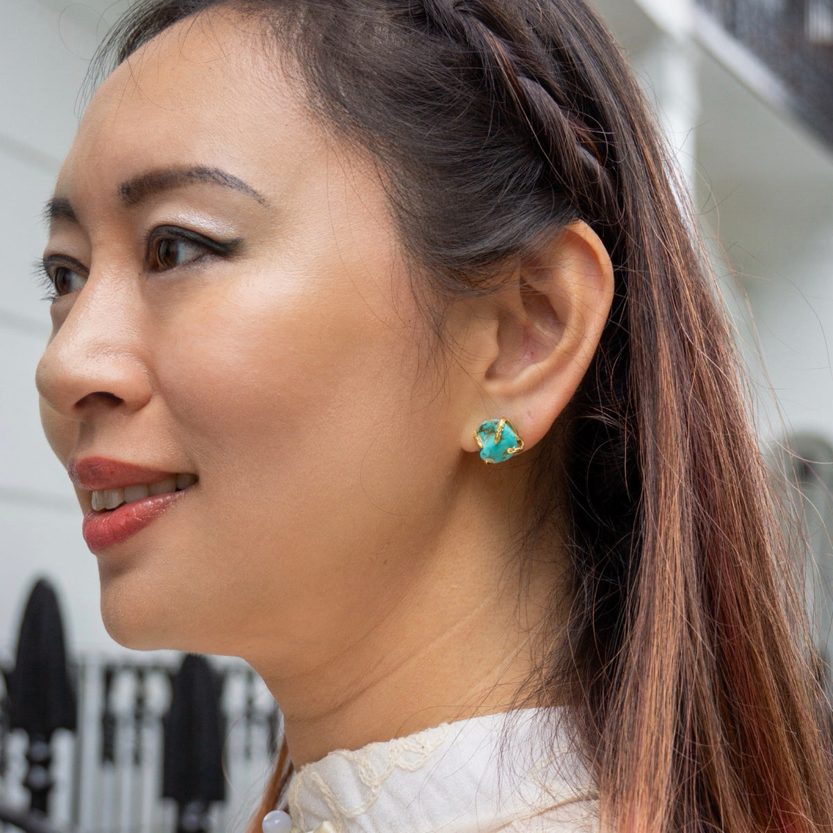 Close-up of a woman wearing turquoise earrings with a blurred background