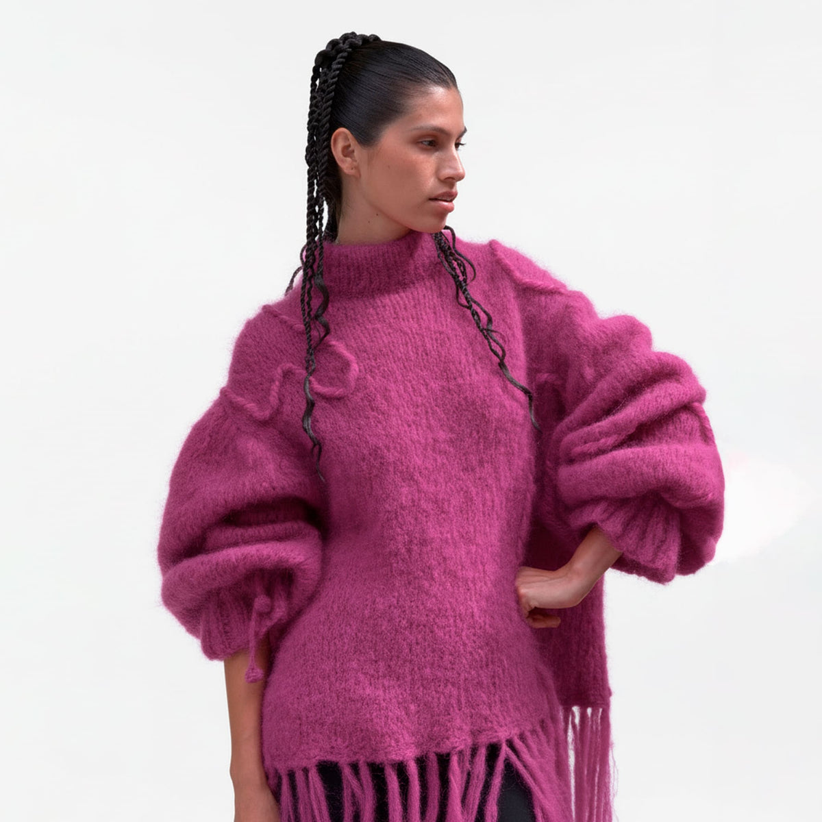 Woman wearing a bright pink sweater with fringes on a white background