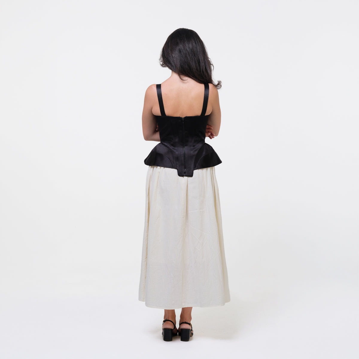 Woman wearing a black top and white skirt on a white background