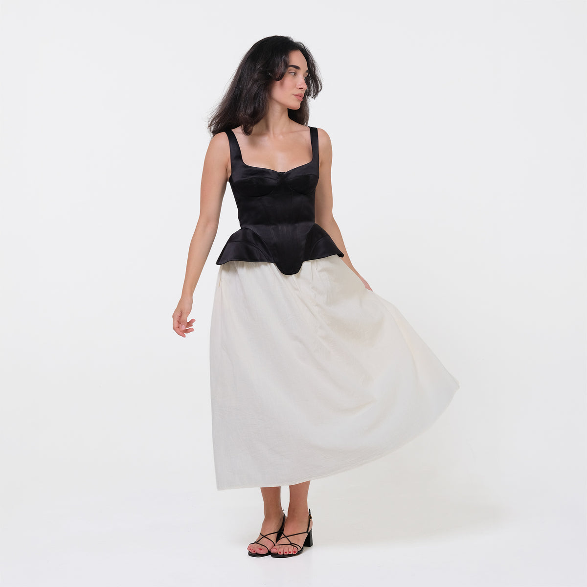 Woman wearing a black top and white skirt on a white background