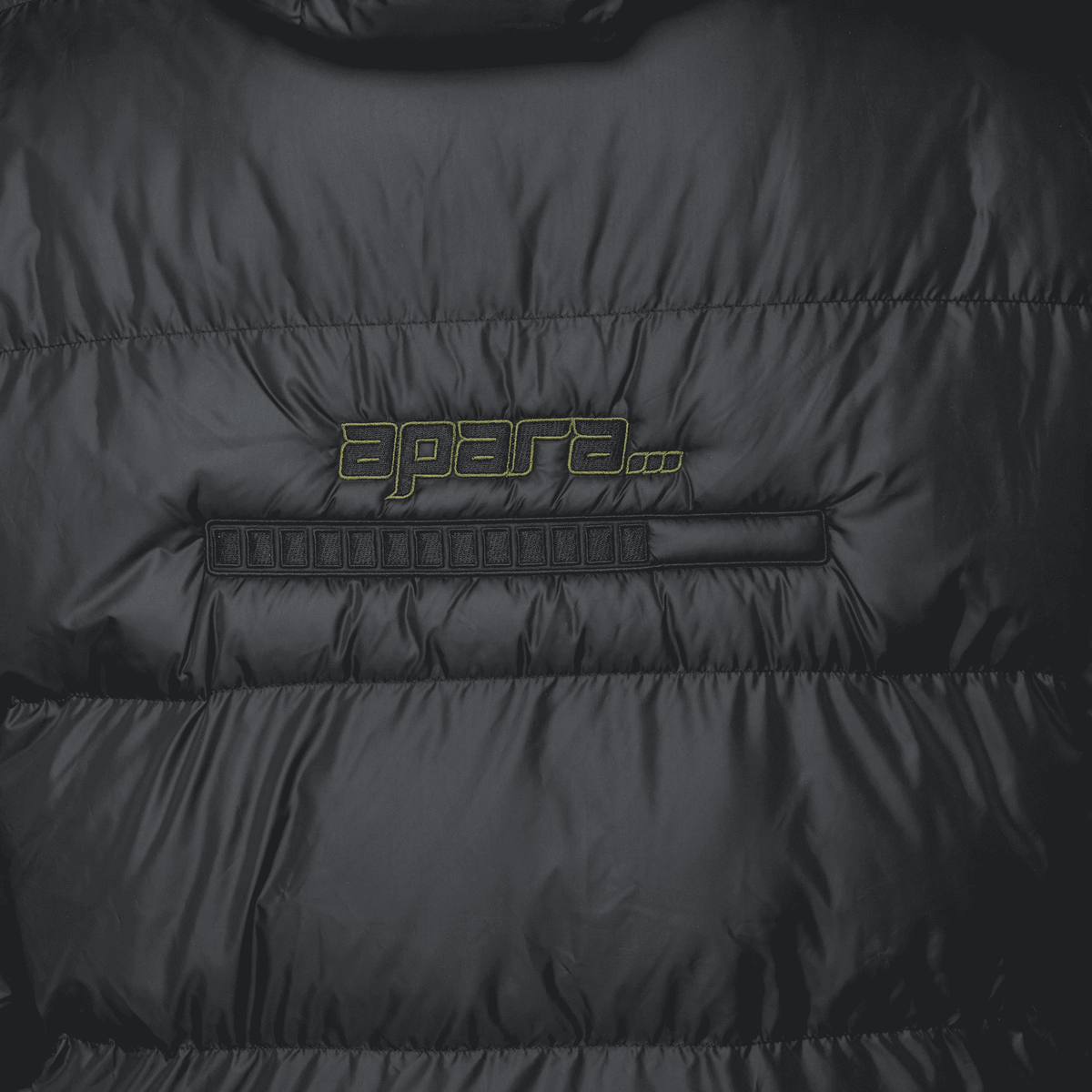Close-up of a black puffer jacket with 'apart' branding on a dark background