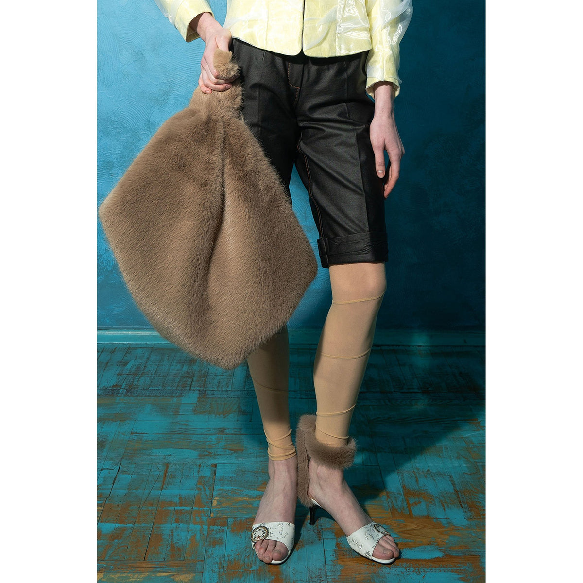 Model wearing black wrinkled faux leather shorts with tan stitching by MASHAT