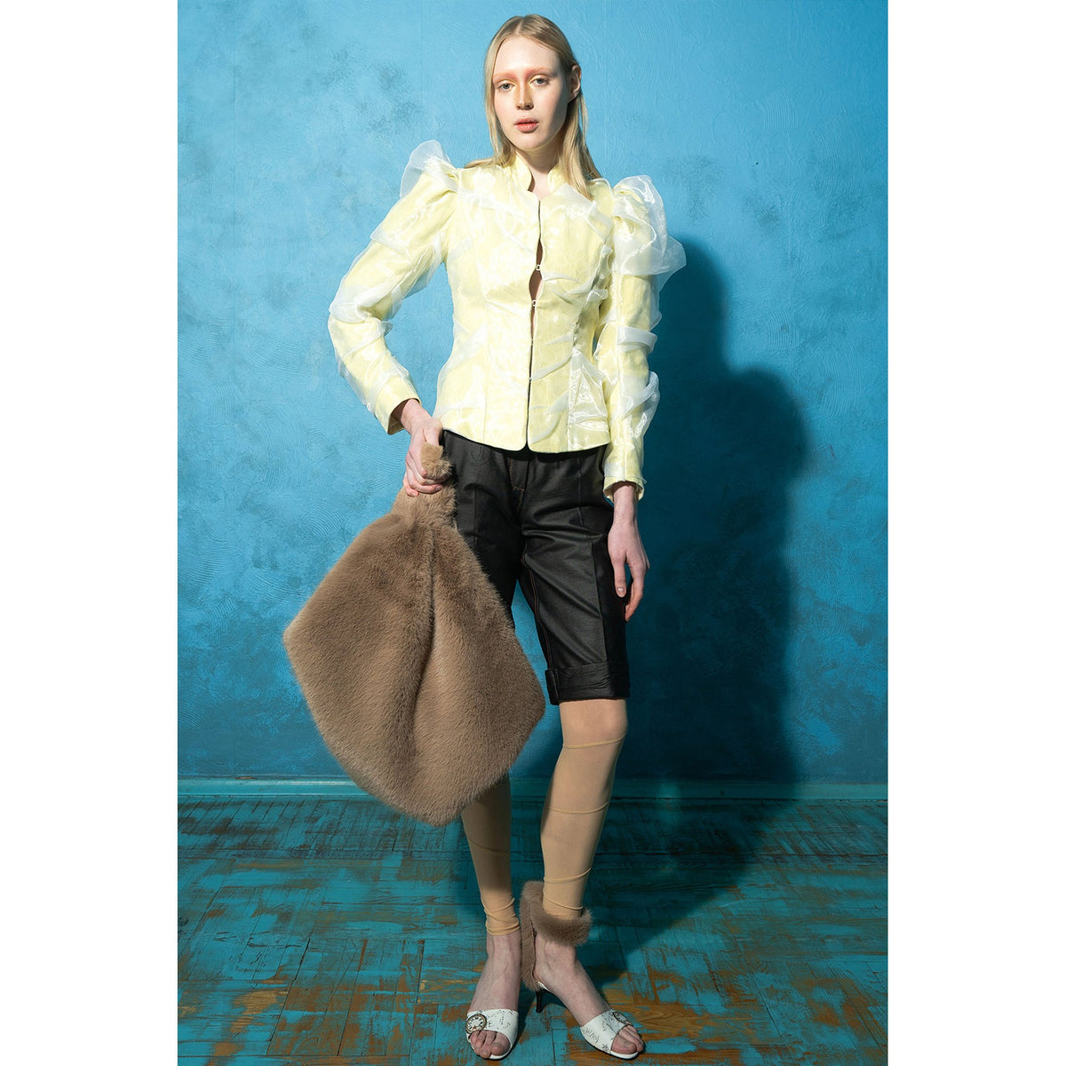 Model wearing black wrinkled faux leather shorts with tan stitching by MASHAT