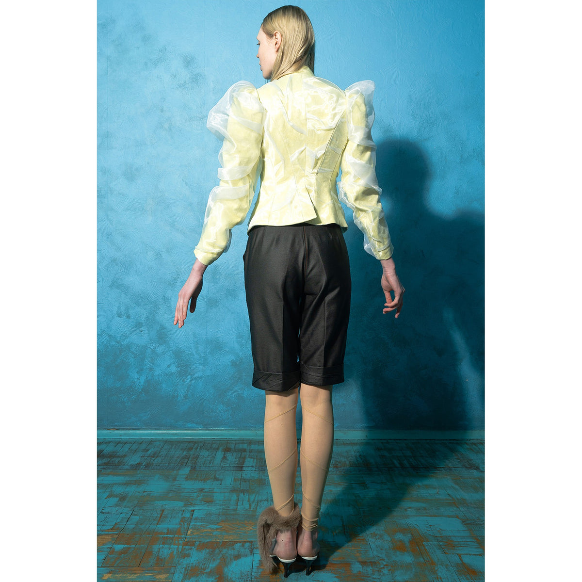 Model wearing black wrinkled faux leather shorts with tan stitching by MASHAT