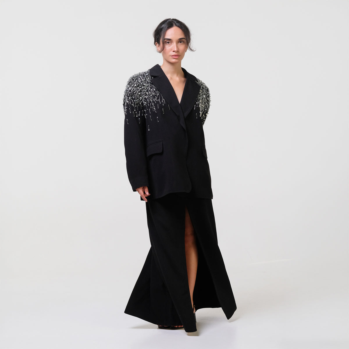 Woman wearing a black coat with embellished shoulders on a white background