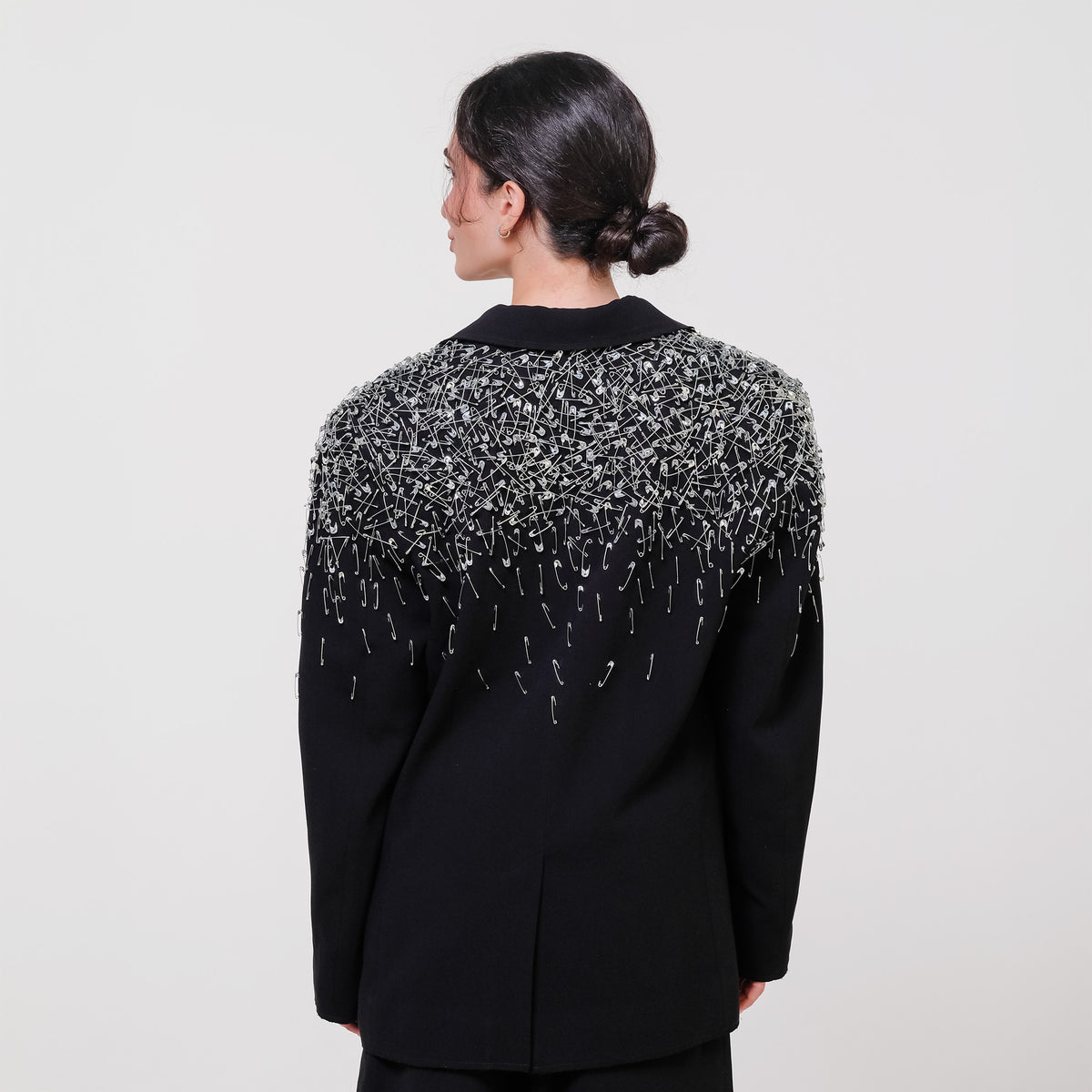 Black blazer with intricate silver beading on a plain background