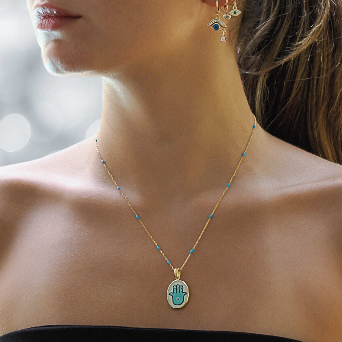 Model Sporting an Elegant Hamsa Hand Pendant Necklace with Turquoise Enamel.