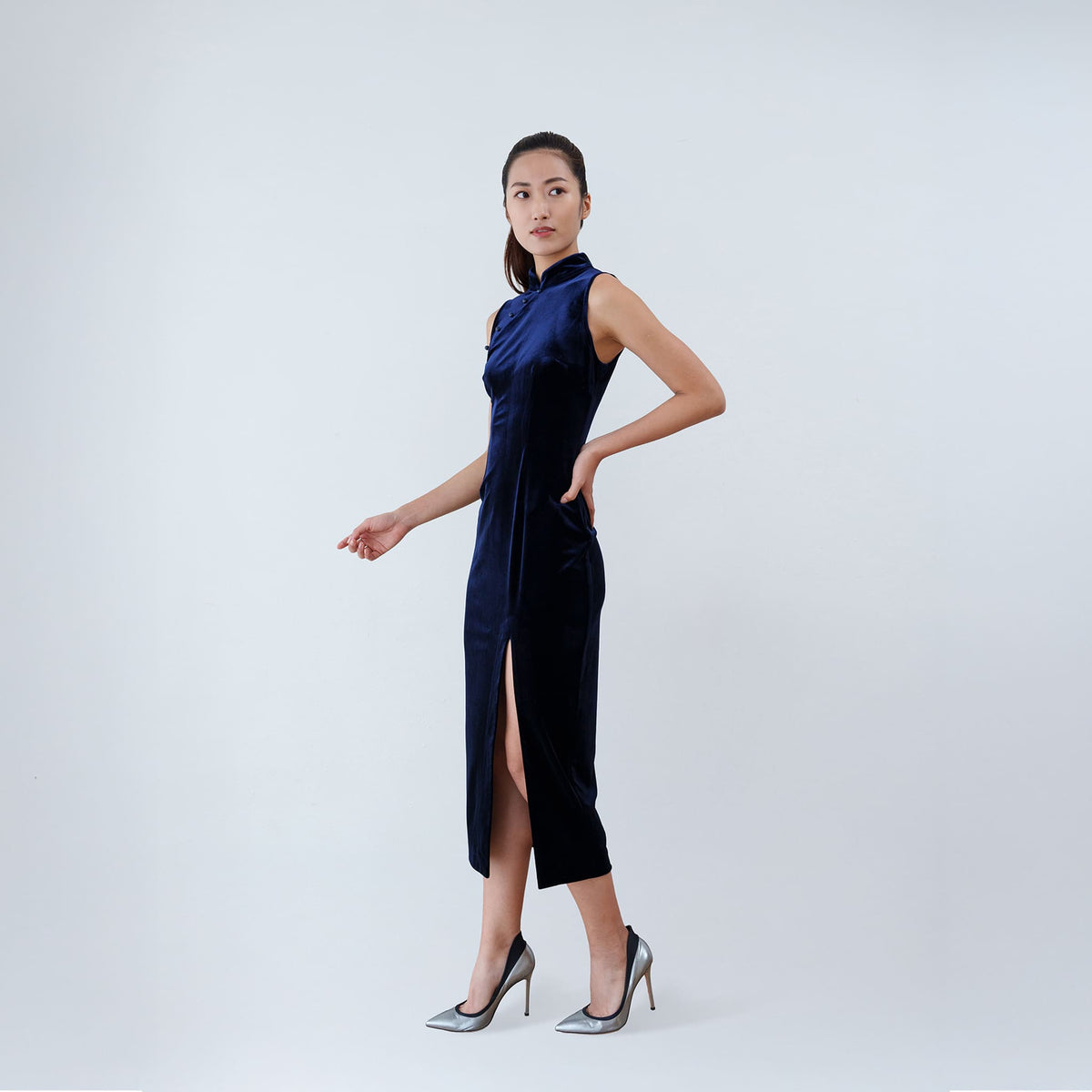 Qipology navy blue velvet sleeveless qipao dress with Mandarin collar, beaded detail and front slit, worn by model, look 2, buy at DOORS NYC
