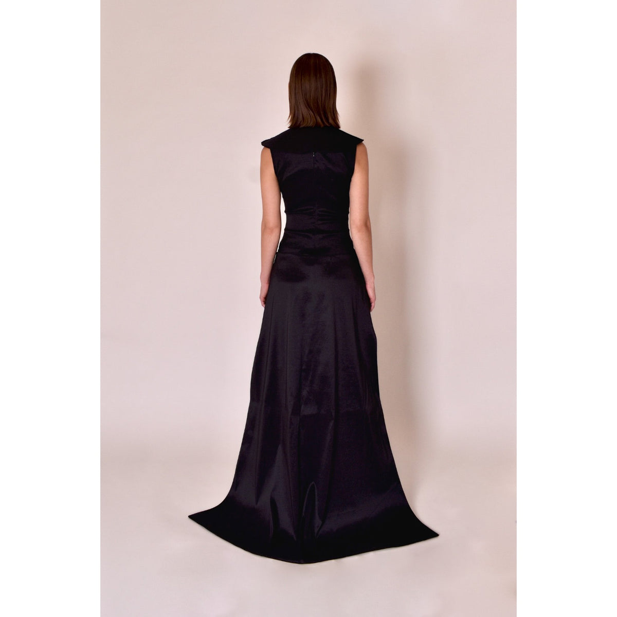 Woman wearing a black evening gown against a plain background