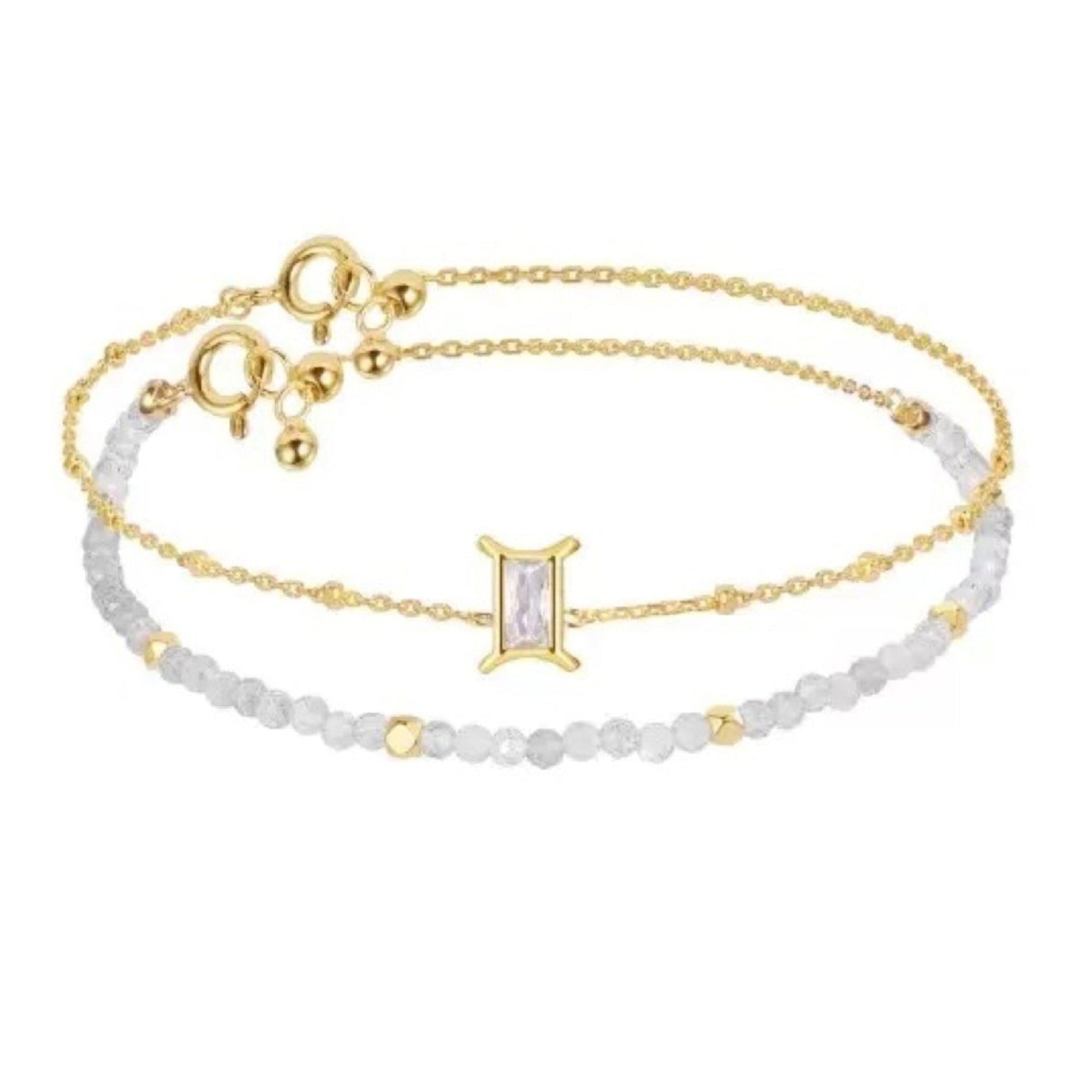 Two gold bracelets with a white beaded band on a white background